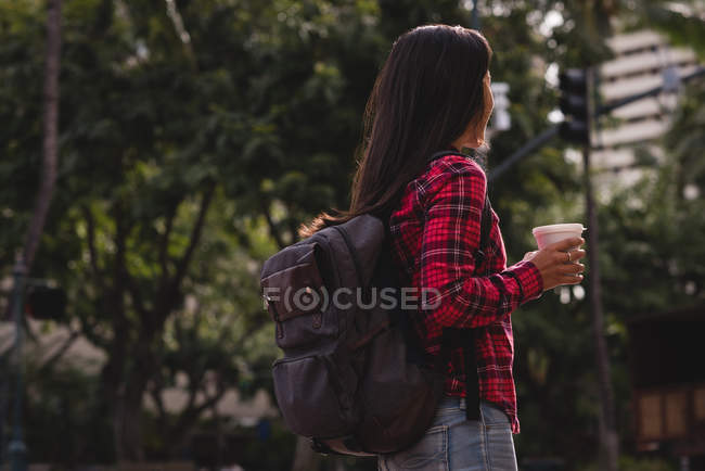 Вид збоку жінки з чашкою кави, що стоїть на вулиці — стокове фото