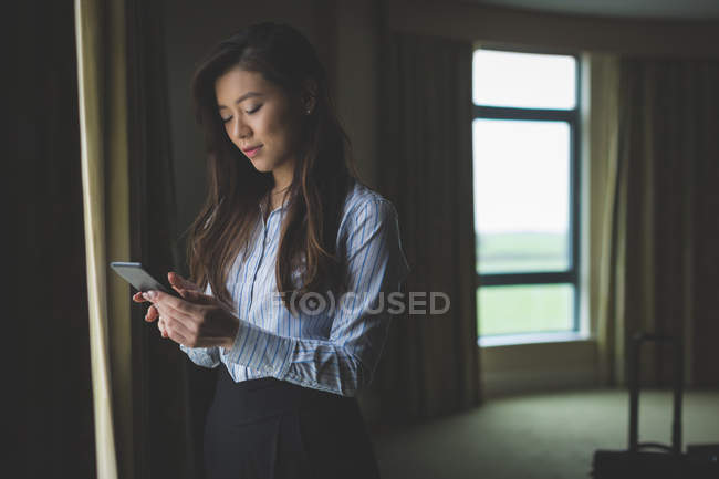 Бізнес-леді, використовуючи мобільний телефон в готельному номері — стокове фото