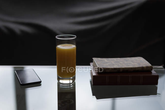 Cellulare, succo d'arancia e diario sul tavolo a casa . — Foto stock