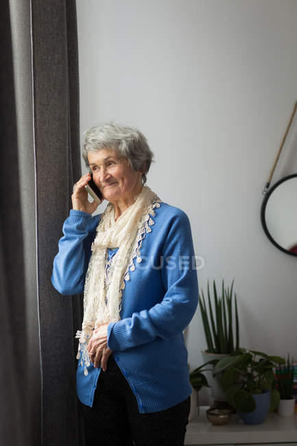 Senior woman talking on mobile phone at home — Stock Photo