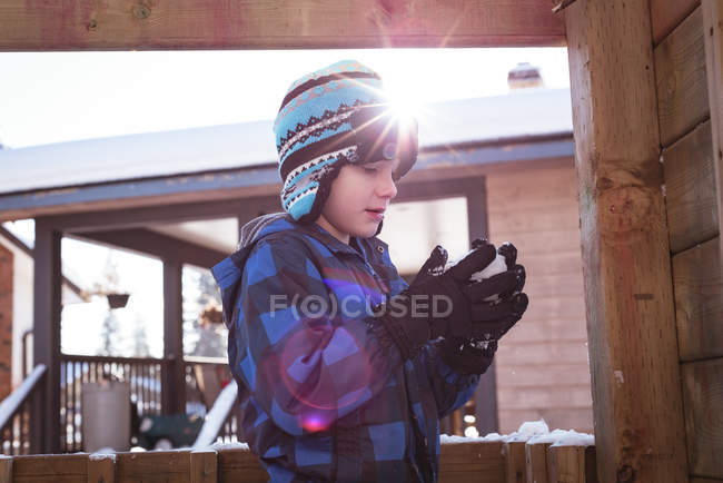 Bonito menino segurando bola de neve durante o inverno — Fotografia de Stock