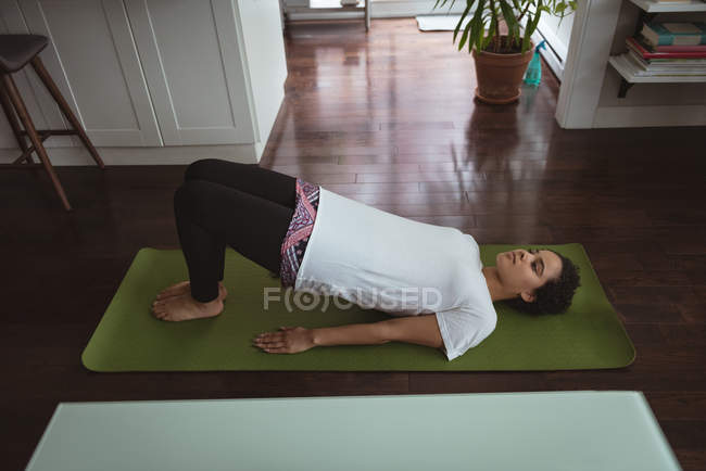 Jovem realizando ioga no tapete de ioga em casa — Fotografia de Stock