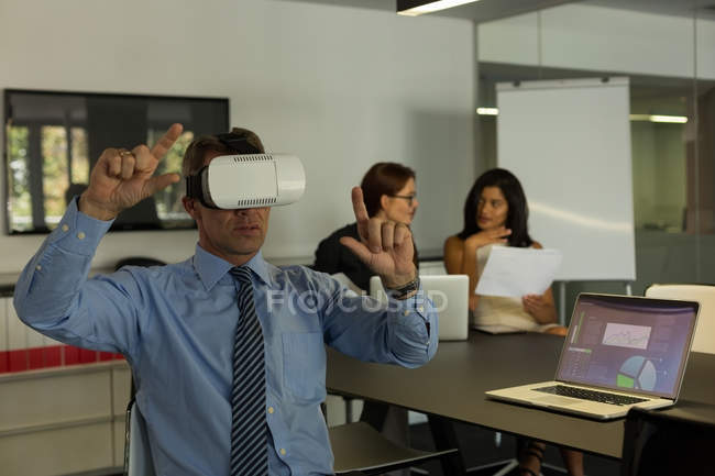 Hombre de negocios usando auriculares de realidad virtual en la sala de conferencias en casa - foto de stock