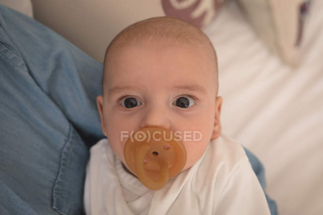 Portrait of cute little baby with pacifier in mouth looking into camera — Stock Photo