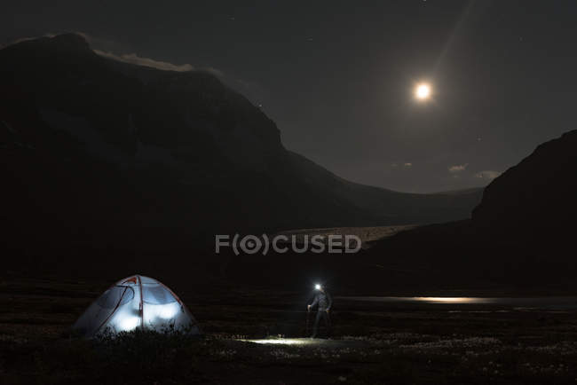 Male hiker walking towards tent at night — Stock Photo