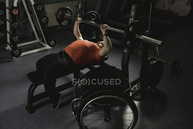 Uomo handicappato che fa allenamento al petto sulla panca con bilanciere in palestra — Foto stock