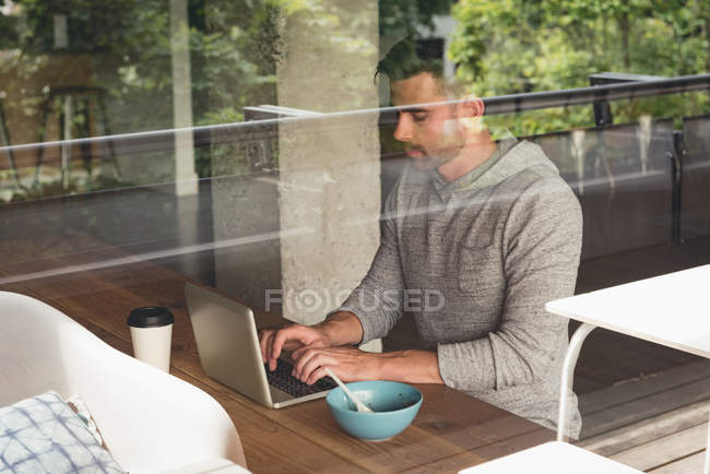 Businessman using laptop in cafeteria at office — Stock Photo