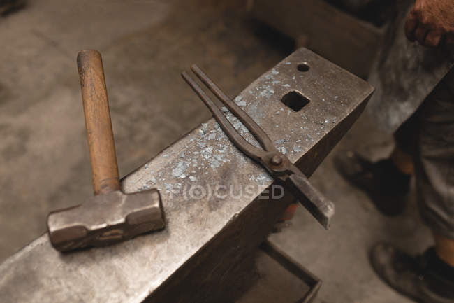 Gros plan du marteau et de la pince sur enclume en atelier — Photo de stock