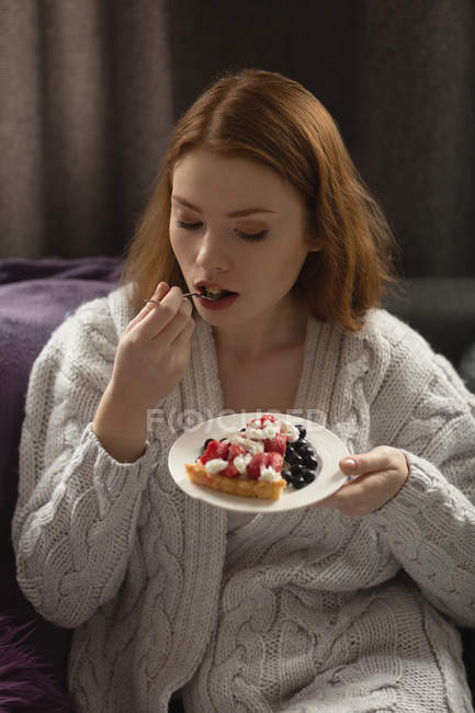 Молодая женщина ест десерт дома — стоковое фото