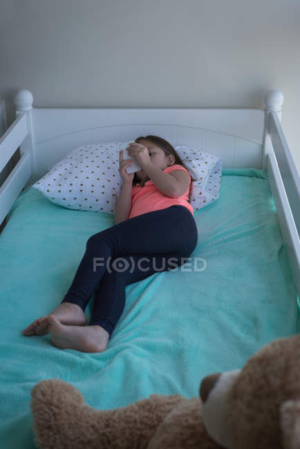 Elementary age girl using mobile phone in bedroom at home — Stock Photo