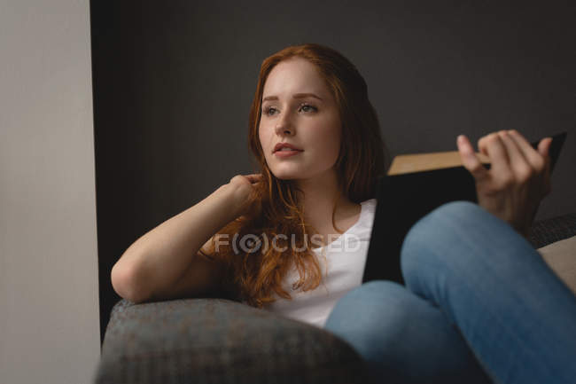 Nachdenkliche Frau liest zu Hause ein Buch — Stockfoto