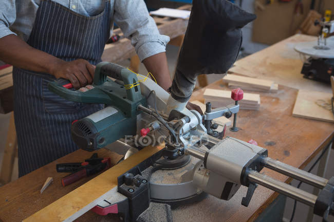 Section médiane du charpentier coupant la planche en bois avec la scie électrique dans l'atelier — Photo de stock