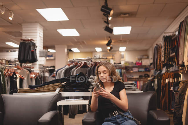 Bella ragazza che utilizza il telefono cellulare sul divano al centro commerciale — Foto stock