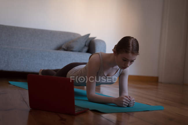 Mulher praticando prancha posar na sala de estar em casa — Fotografia de Stock
