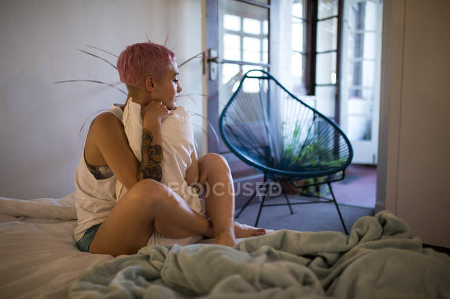 Jeune femme se détendre dans la chambre et étreindre oreiller à la maison . — Photo de stock