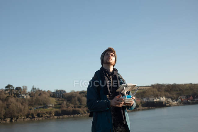 Homme randonneur opérant drone près du lac à la campagne — Photo de stock