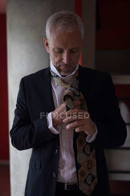 Businessman tying his tie in hotel room — Stock Photo