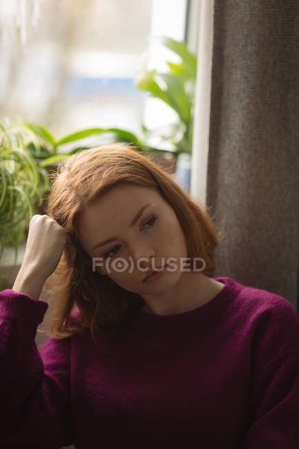 Femme réfléchie debout près de la fenêtre à la maison — Photo de stock