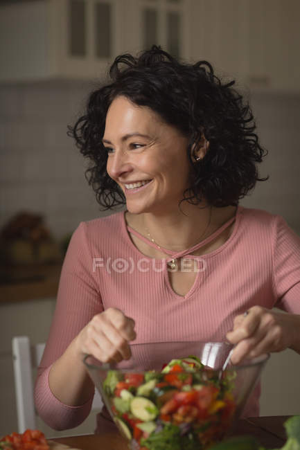Mulher preparando salada de legumes na cozinha em casa — Fotografia de Stock