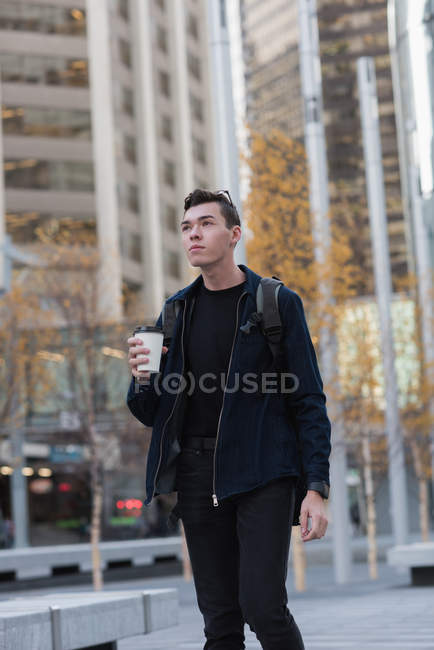 Uomo premuroso che cammina per strada mentre prende un caffè — Foto stock
