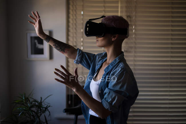 Jovem mulher adulta usando fone de ouvido realidade virtual em casa . — Fotografia de Stock