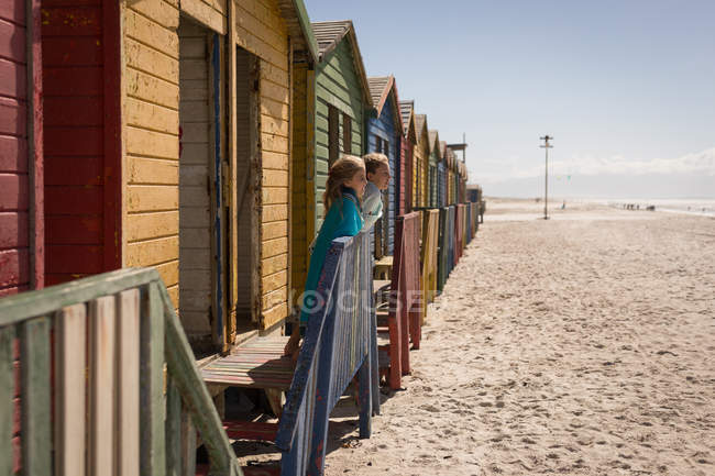 Братья и сёстры стоят рядом с пляжной хижиной в солнечный день — стоковое фото