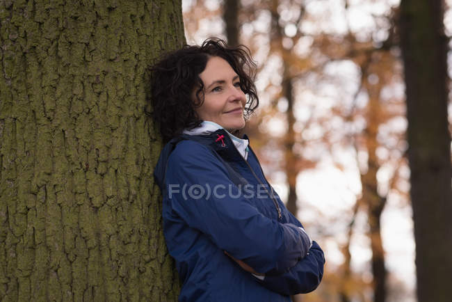 Задумчивая женщина, стоящая со скрещенными руками в парке — стоковое фото