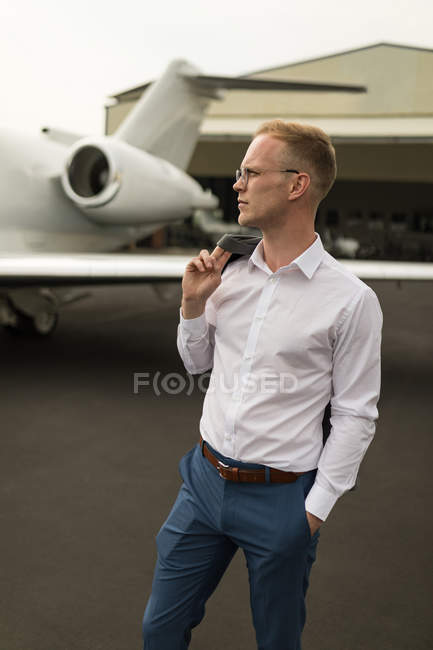 Thoughtful businessman standing at terminal with jacket — Stock Photo