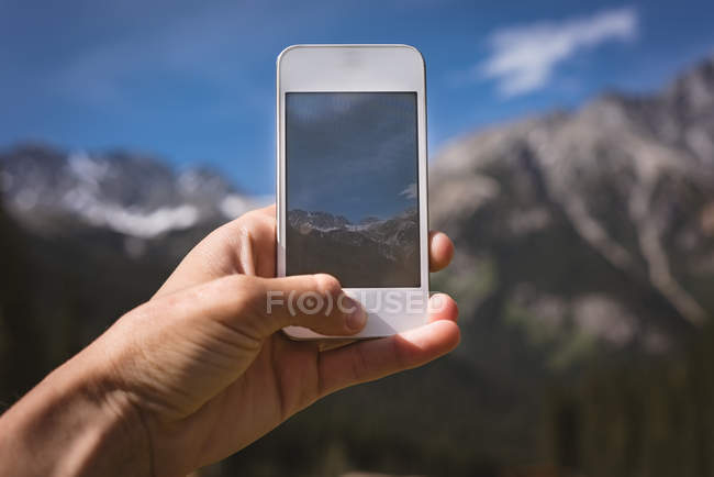 Nahaufnahme eines Mannes, der mit seinem Handy Berge fotografiert — Stockfoto