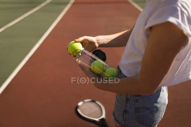 Средняя часть женщины снимает теннисный мяч с футляра для теннисного мяча — стоковое фото