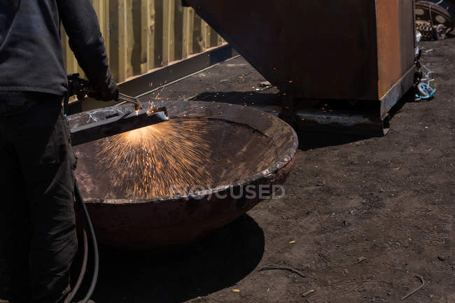 Seção média de trabalhador soldando a estrutura de metal no scrapyard — Fotografia de Stock