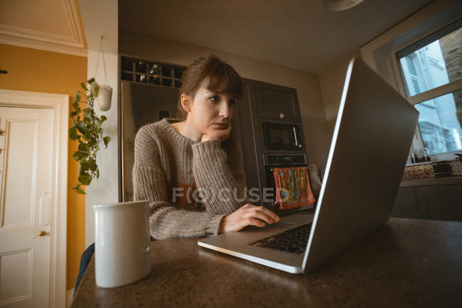 Жінка використовує ноутбук на кухні вдома — стокове фото