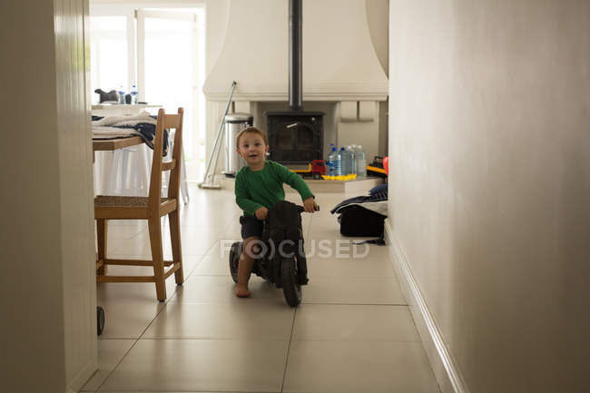 Petit garçon chevauchant un tricycle à la maison — Photo de stock