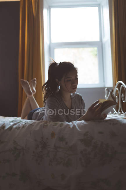 Mulher lendo um livro no quarto em casa — Fotografia de Stock