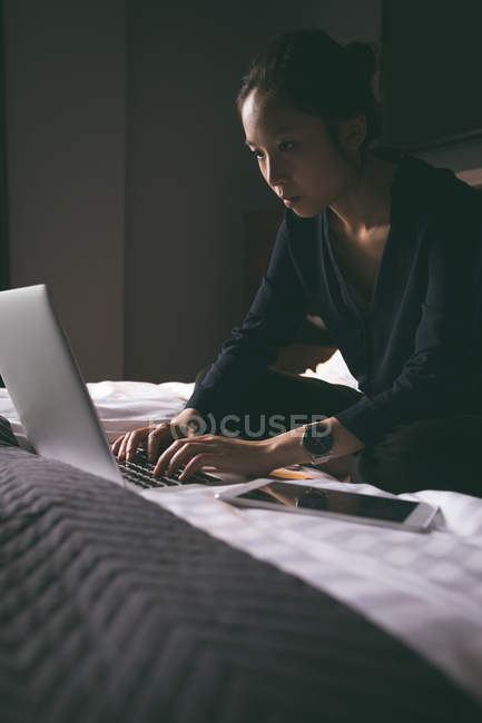 Frau benutzt Handy beim Entspannen im Hotelbett — Stockfoto