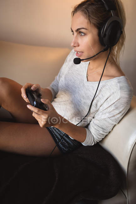 Donna che gioca al videogioco con auricolare in soggiorno a casa — Foto stock