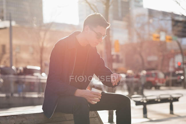 Homem verificando o tempo enquanto toma café na rua — Fotografia de Stock