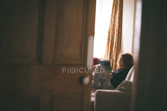 Mulher lendo um livro na sala de estar — Fotografia de Stock
