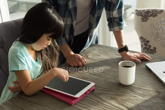 Father and daughter using digital tablet at home — Stock Photo