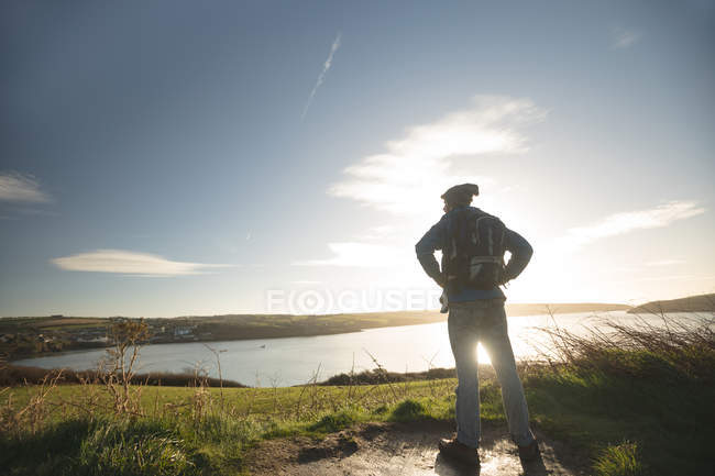 Visão traseira do caminhante masculino em pé perto do rio no campo — Fotografia de Stock