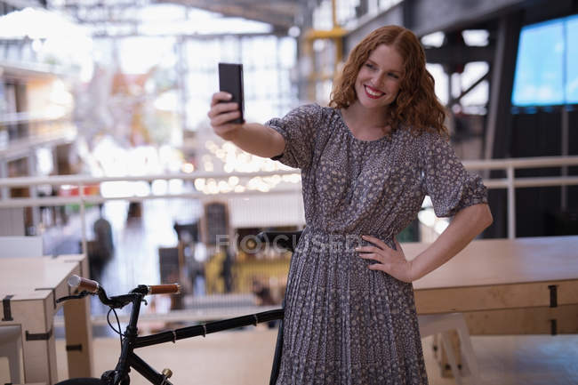 Feliz mujer ejecutiva tomando selfie con teléfono móvil en la oficina - foto de stock