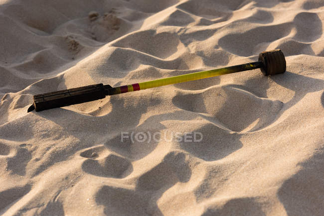 Primo piano di fuoco levi bastone sulla sabbia della spiaggia alla luce del sole — Foto stock