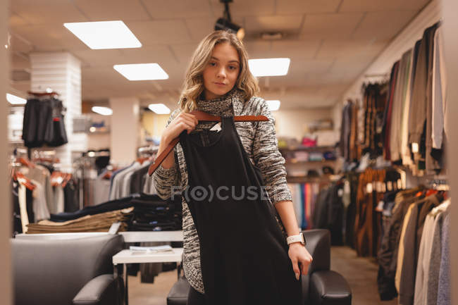Portrait of beautiful girl checking out the dress in shopping mall — Stock Photo