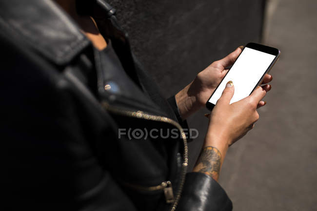 Середина жінки в шкіряній куртці з використанням мобільного телефону . — стокове фото