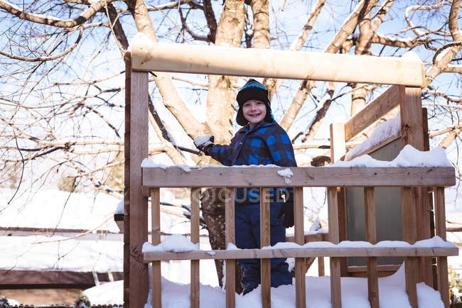 Портрет милого мальчика, играющего со снежком на детской площадке зимой — стоковое фото