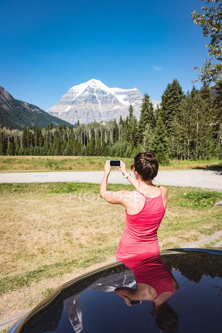 Женщина фотографируется с мобильного телефона в солнечный день — стоковое фото