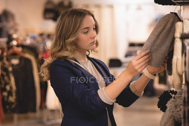 Beautiful girl checking out hat in display at shopping mall — Stock Photo