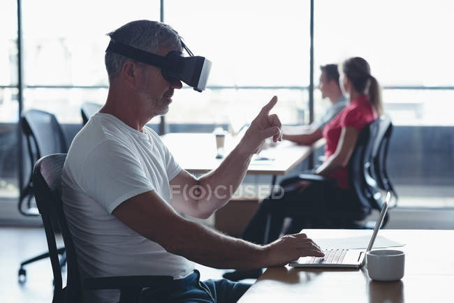 Бізнесмен, використовуючи гарнітуру віртуальної реальності за столом в офісі — стокове фото