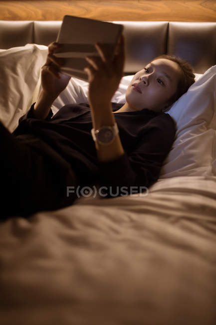Frau nutzt digitales Tablet beim Entspannen im Hotelbett — Stockfoto
