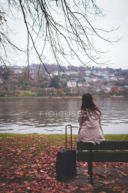 Вид спереду бізнес-леді сидить на лавці біля берега озера — стокове фото
